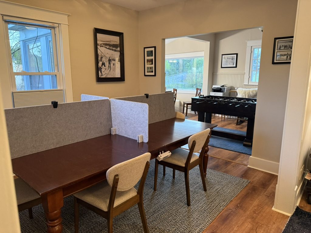 The Eiswork conference table with divider screens and chairs, the game room visible through the doorway