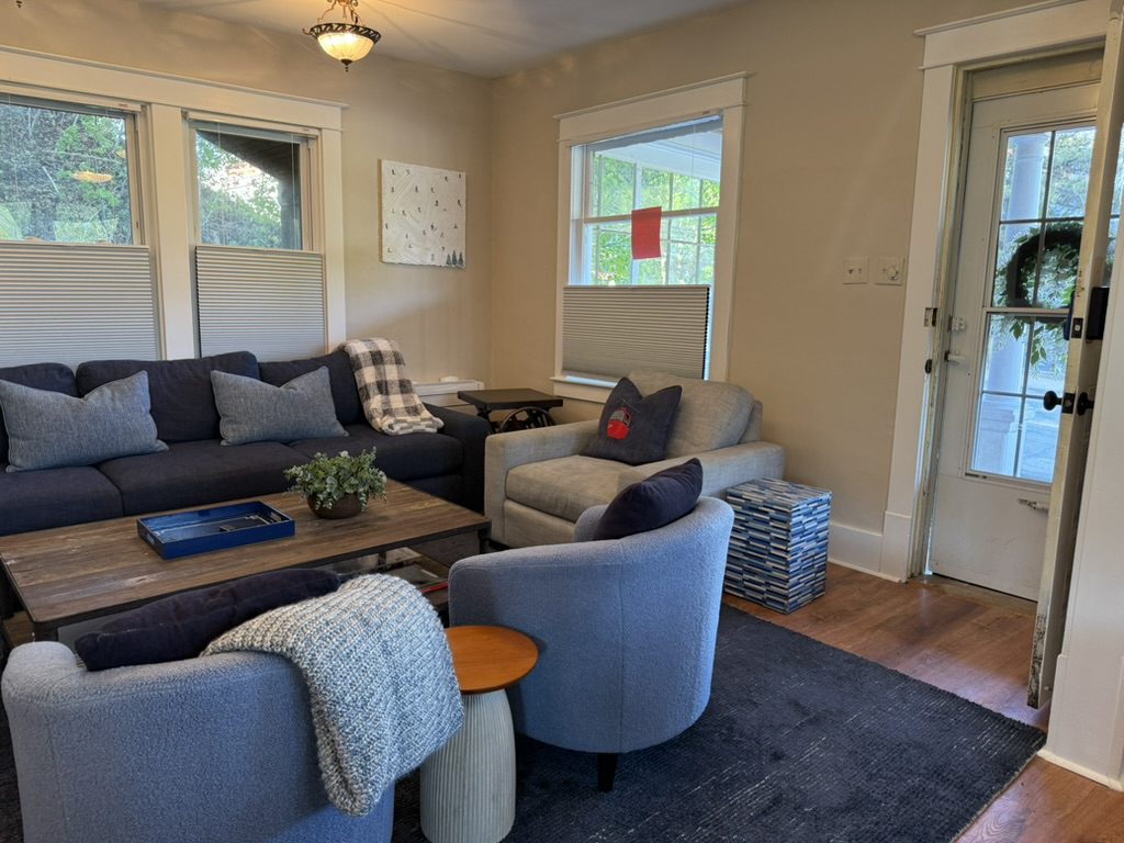 The Eiswork lounge — sofa, bouclé armchairs, a low table and a blanket, with the door to Main Street