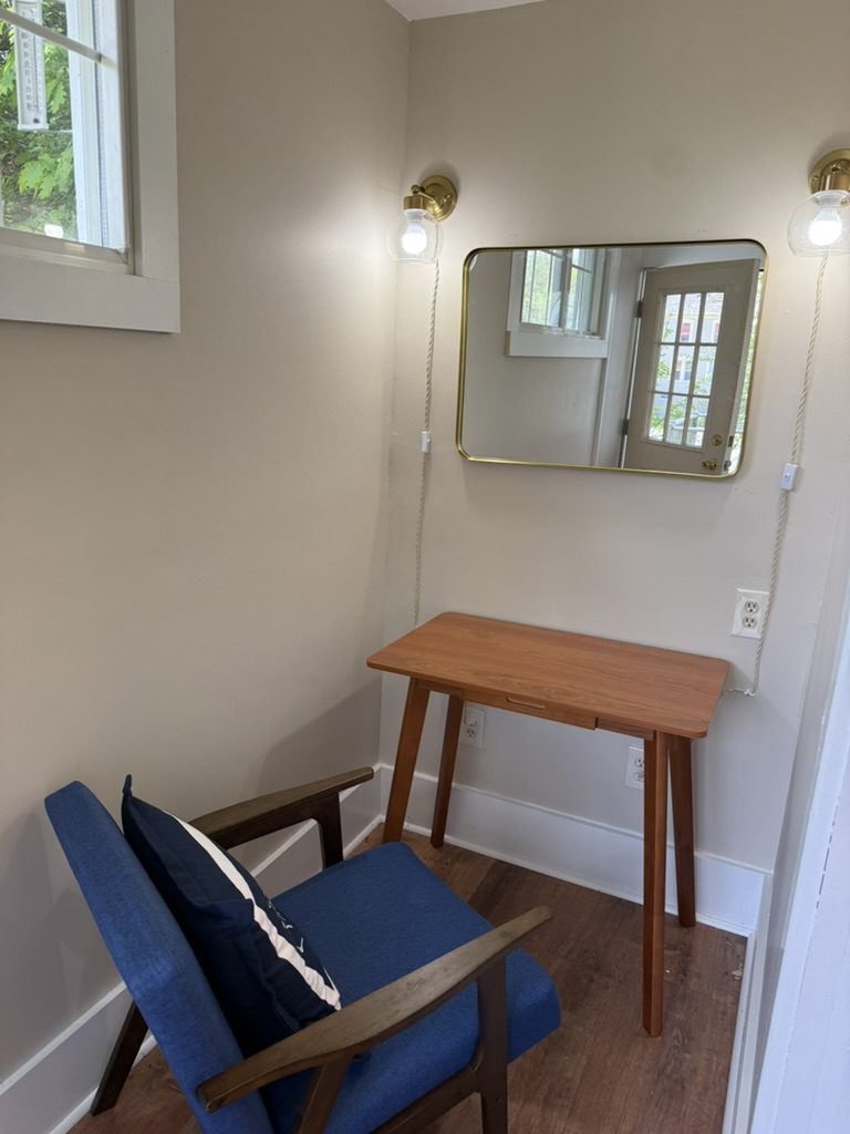 The private desk at Eiswork — a wooden table and blue chair under a mirror and wall sconces in a separated space