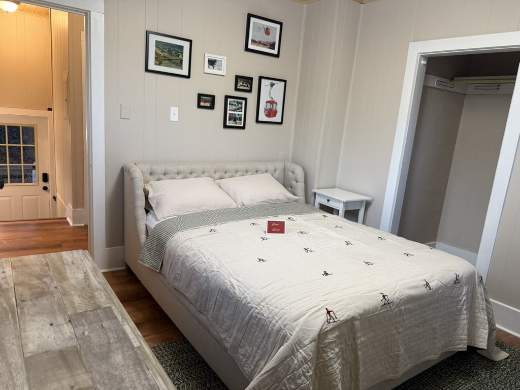 Third bedroom in the Eiswork Loft at 235 Main Street — a tufted headboard, framed vintage gondola and ski photographs, and a closet